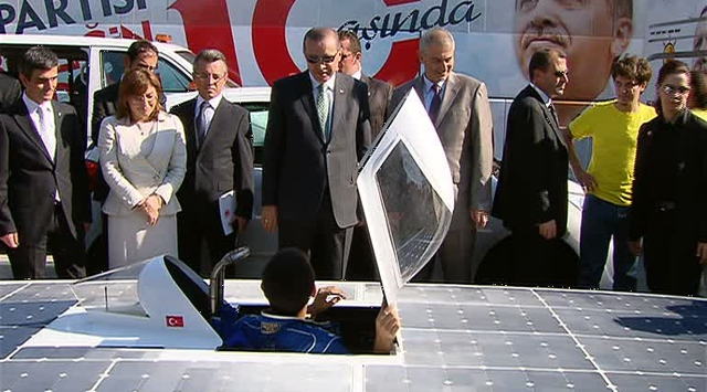 Erdoğan Üniversiteli gençlerin geliştirdiği Solar / Güneş aracını incelerken. 
Arkadaki AK Parti 10 yaşında! ibaresine dikkat.